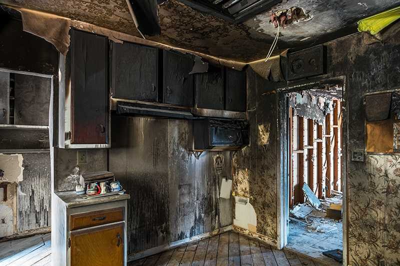 Fire-damaged kitchen with charred walls and cabinets